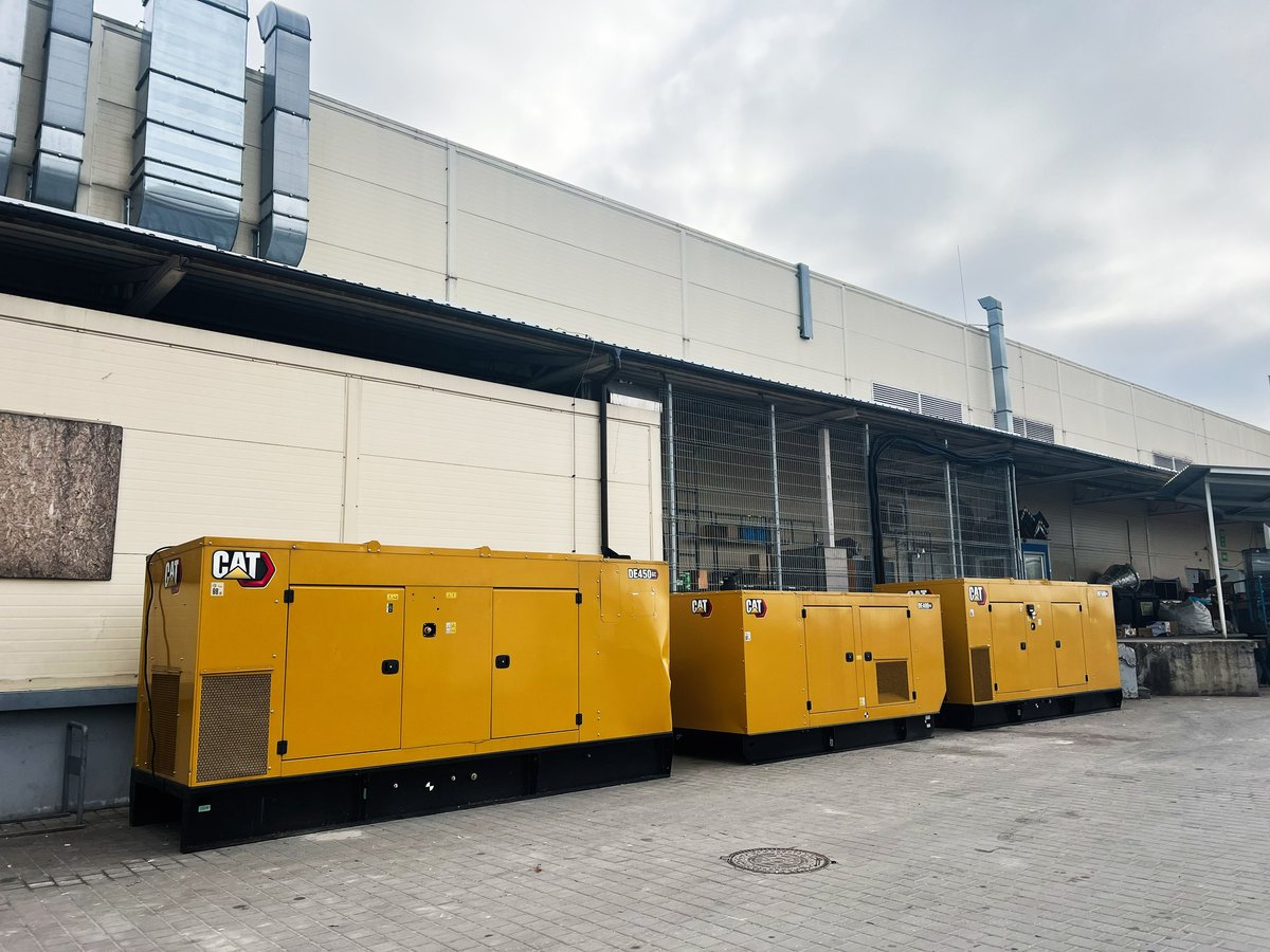 Múltiples generadores industriales CAT alineados en exterior de edificio comercial para respaldo energético