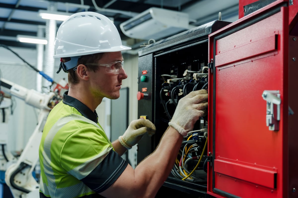 Ingeniero realizando inspección y mantenimiento eléctrico en tablero de control industrial