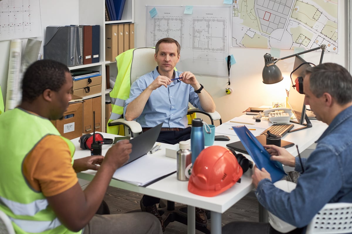 Engineering team discussing construction plans and reviewing electrical documents