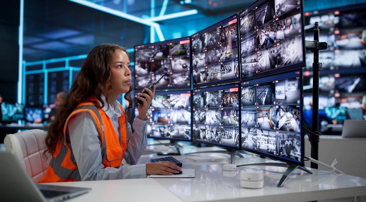 Centro de monitoreo con guardia de seguridad supervisando múltiples cámaras CCTV