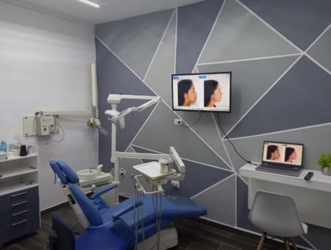 Modern dental office with blue chair and wall-mounted screens