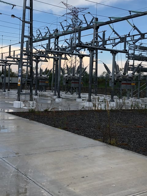 Industrial electrical substation with complex network of power lines, transformers, and metal structures against a cloudy sky