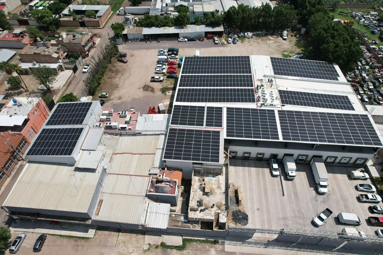 Vista aérea de edificios industriales con paneles solares instalados en los techos y vehículos estacionados