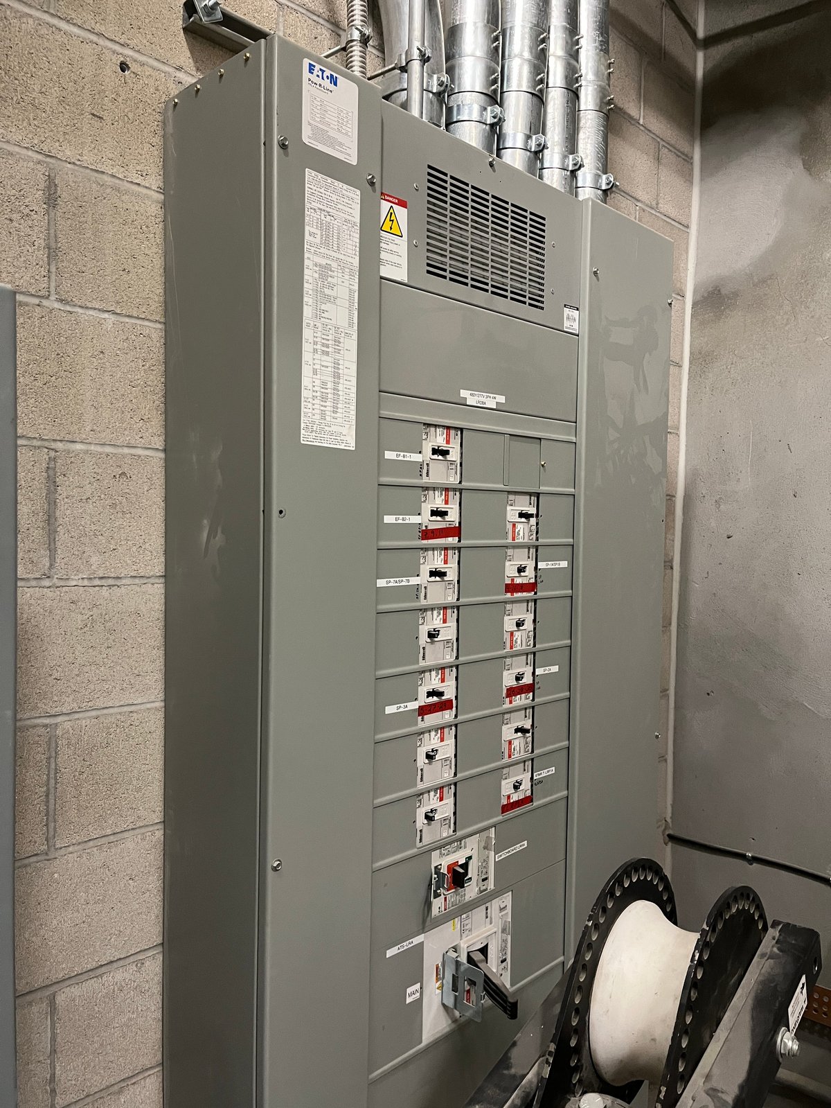 Tablero eléctrico industrial con interruptores y tubería conduit en muro de concreto