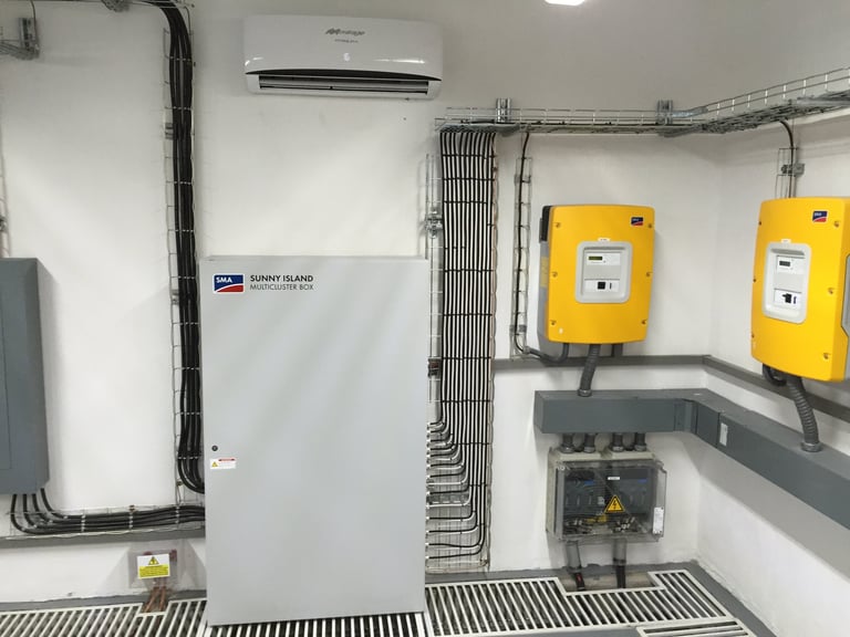 Industrial electrical panel with white central unit, yellow circuit breakers, conduit piping, and wall-mounted equipment