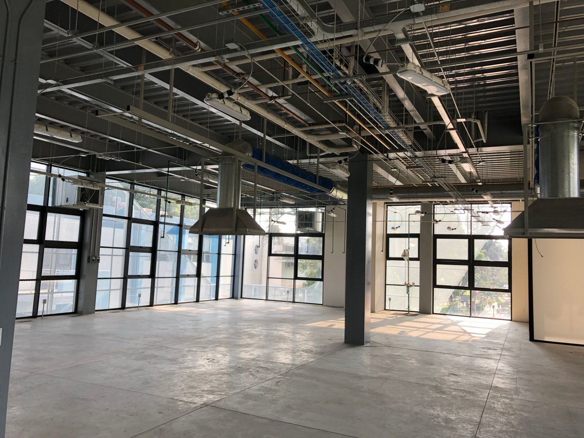 Nave industrial diáfana con ventanales, piso de concreto y techos expuestos