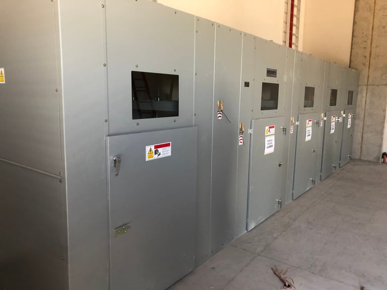 Fila de gabinetes eléctricos industriales grises y paneles de control en un almacén