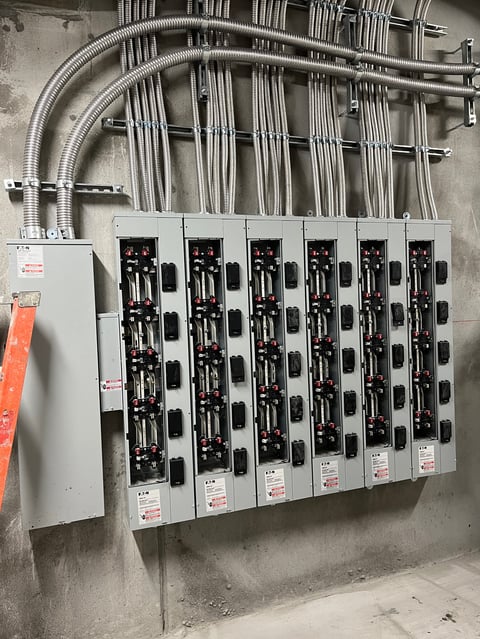 Tablero eléctrico con seis cajas de interruptores montadas en pared de concreto, conectadas a tubería conduit metálica curva